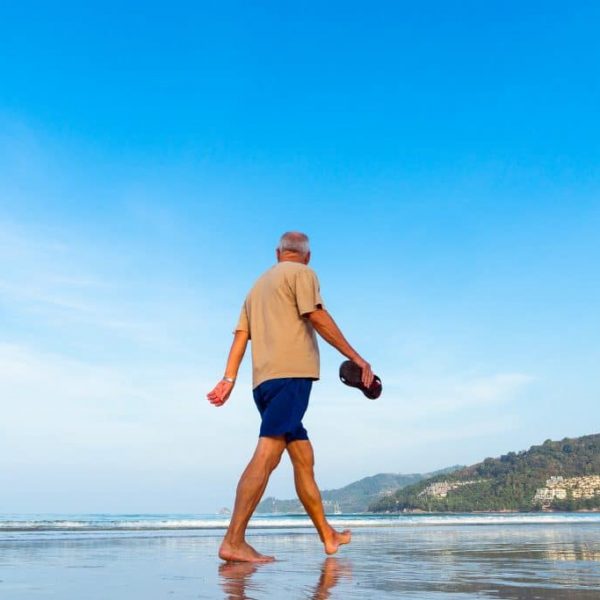 Older person walking on beach