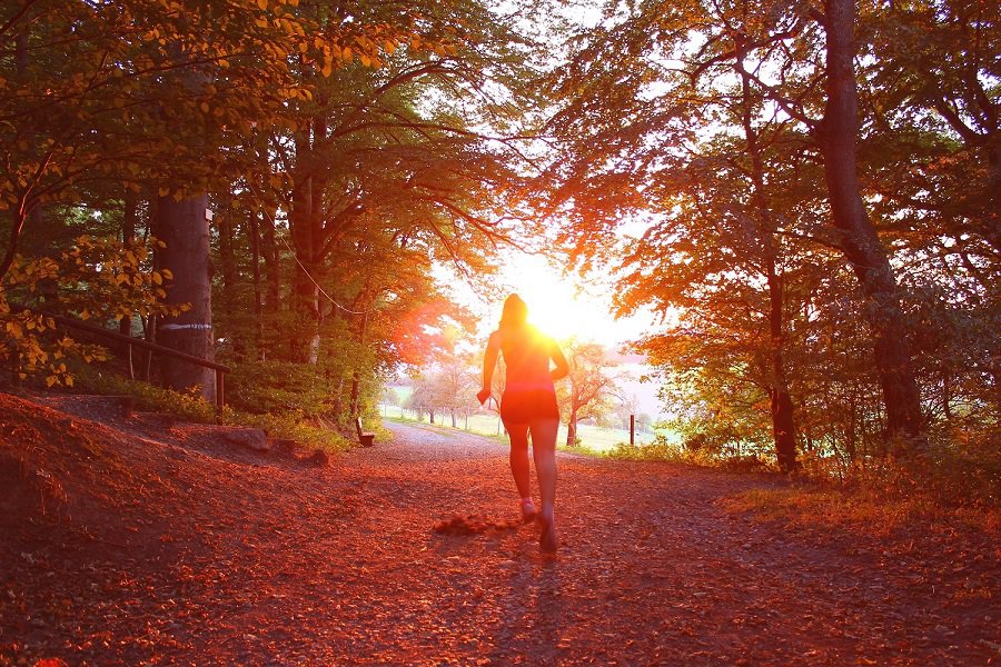 Woman running in forest near sunset
