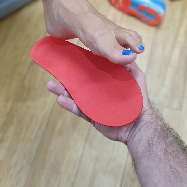 Red orthotic being checked against foot contour