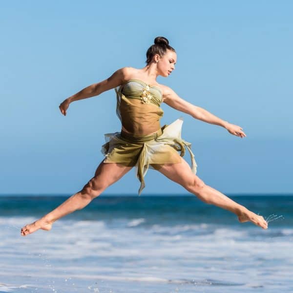 Dancer dancing on the beach with waves in background