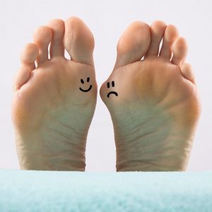 Right foot with happy face and left foot with bunion and sad face.