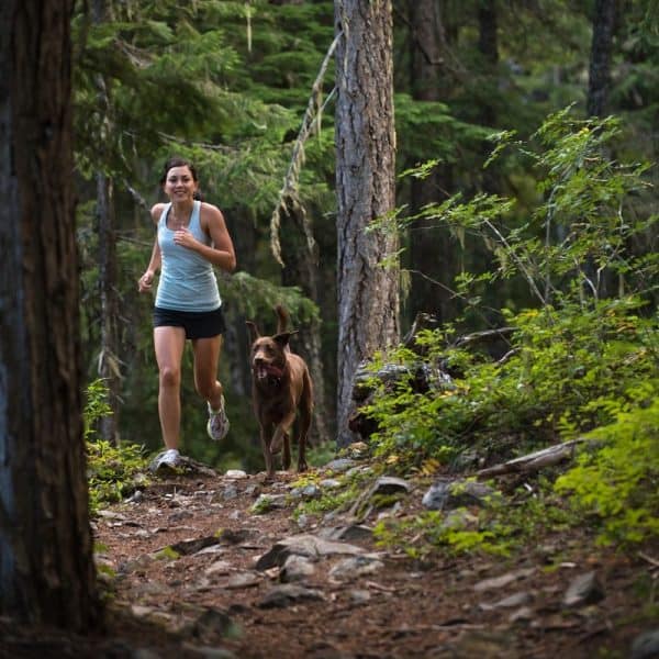 Lady trail running with brown dog
