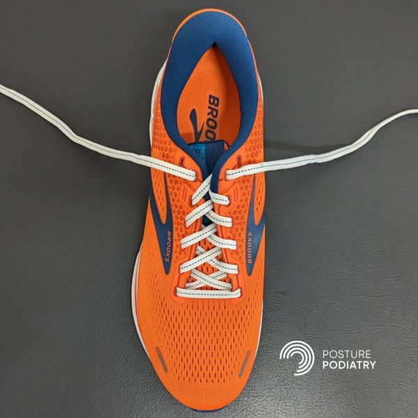 Image displaying orange shoe with conventional crossover shoe lacing