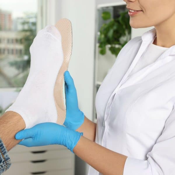 Lady holding orthotic up against foot to check contour