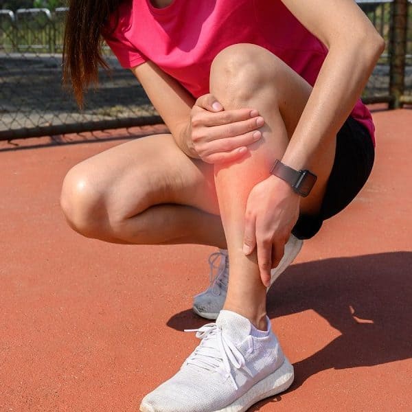 Lady holding lower leg with shin pain