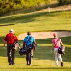 Two men and a lady walking the golf course