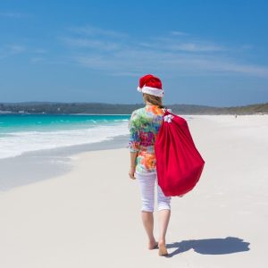 Lady walking along the beach with a sack full of Christmas gifts